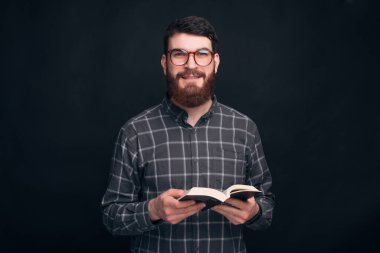 Gözlüklü gülümseyen adam açık bir kitap tutuyor..