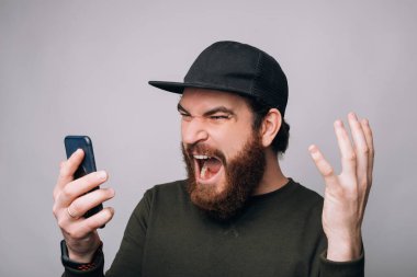 Çığlık atan adam beyaz arka planda telefonuna bakıyor..