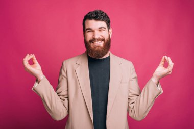 Gülümseyen sakallı adam elleriyle zen jesti yapmaya çalışıyor..