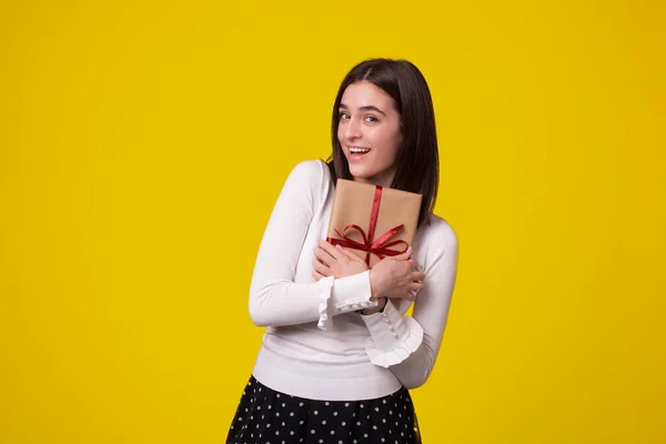 Fröhliche junge Frau, die ein Geschenk in die Kamera hält. — Stockfoto