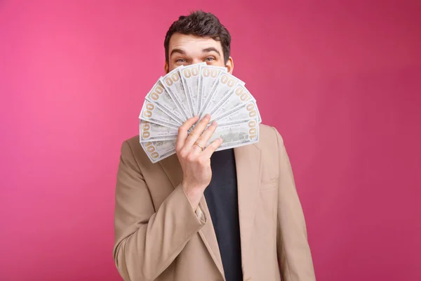 Happy bearded man is covering his face with a bunch of dollars and money. — Stock Photo, Image