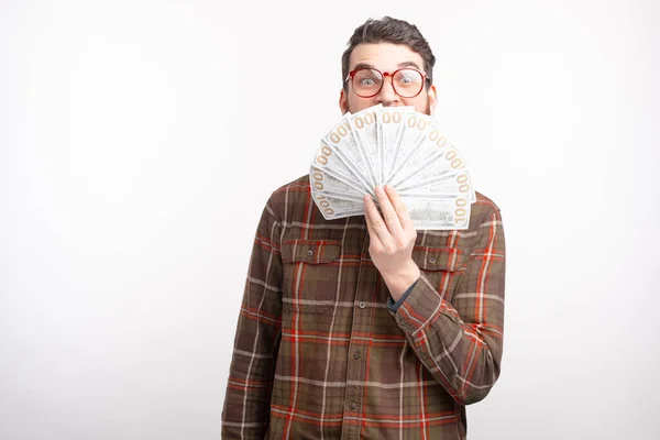Hombre excitado está cubriendo su cara con un ventilador de dinero sobre fondo blanco . — Foto de Stock