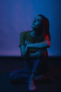 Yerde oturan bir kızın bulanık ve kırmızı ışıklı portresi..