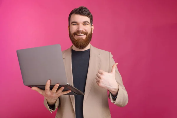 Fröhlicher Mann hält Laptop in der Hand und zeigt Geste. — Stockfoto