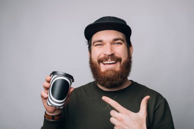 Mutlu adam kağıt bardağını işaret ediyor. Kahvesini götür..