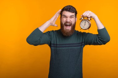 Geç kalma, zamanında gel. Çalar saati tutan adam kameraya bağırıyor..