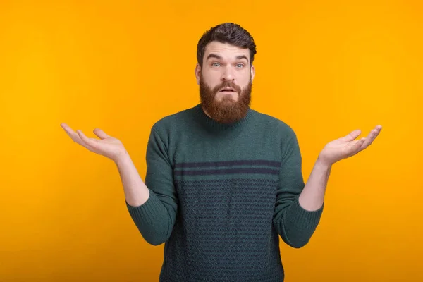 I do not know. Surprised bearded man is shrugging on yellow background.