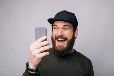 Şaşırmış sakallı adam telefona bakıyor, harika haberleri var..