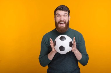 Şaşırmış sakallı adam elinde bir futbol topu ya da futbol topu tutuyor..