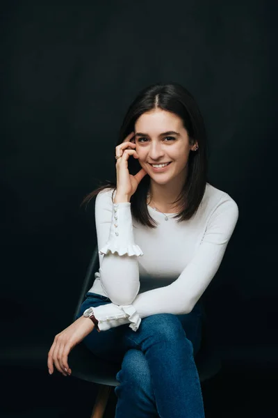 Hermoso retrato de una joven mujer mirando sonriendo a la cámara mientras está sentada en una silla . — Foto de Stock