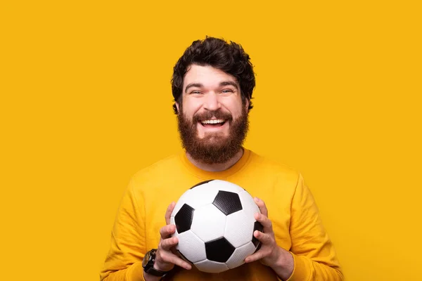 Homem alegre está segurando uma bola de futebol sorrindo para a câmera . — Fotografia de Stock