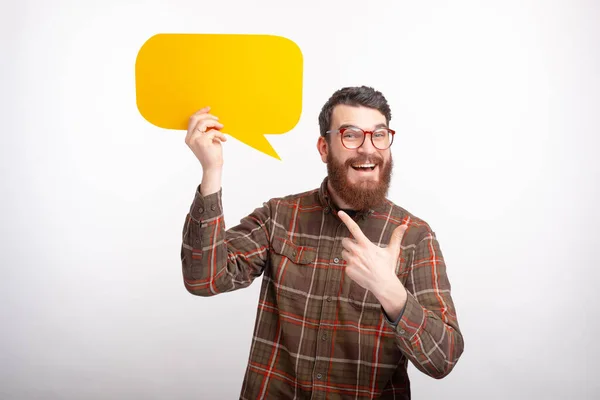 Fröhlich lächelnder Mann zeigt auf eine gelbe Blase Rede steht auf weißem Hintergrund. — Stockfoto