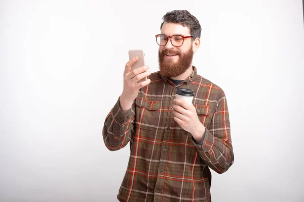 Jovem barbudo homem bebendo café e usando seu smartphone — Fotografia de Stock