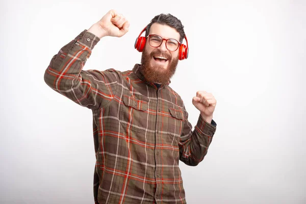 Hombre barbudo feliz con auriculares está bailando sobre fondo blanco . — Foto de Stock