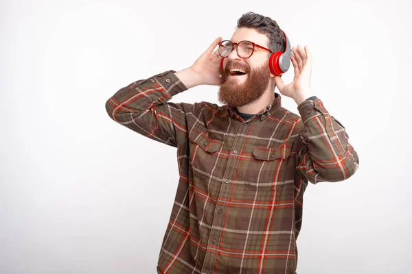 Alegre joven barbudo hombre escuchar música en los auriculares — Foto de Stock