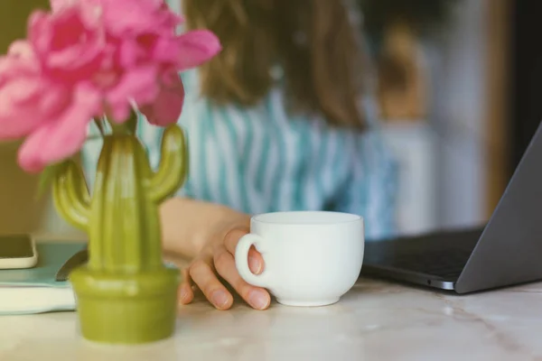 Foto von weiblichen Händen, die eine Tasse Kaffee während der Arbeit auf dem Schoß halten — Stockfoto