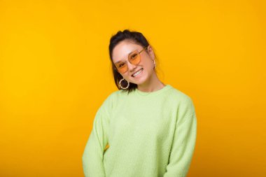 Kameraya gülümseyen, gözlüklü, neşeli genç bir kadının portresi..