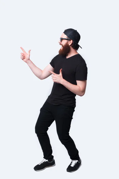 Foto de cuerpo entero del hombre hipster barbudo asombrado apuntando — Foto de Stock