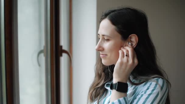 Junge Frau im Büro spricht über drahtlose Kopfhörer — Stockvideo
