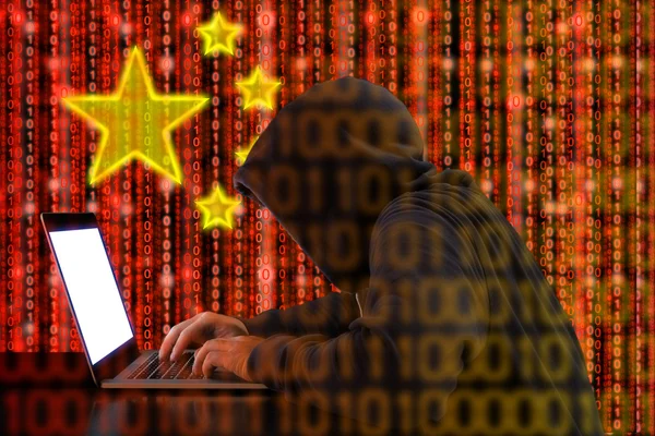 Kinesisk hacker på arbejde foran rødt flag - Stock-foto