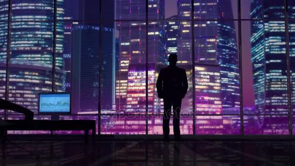 Homme d'affaires dans un bureau sur fond de gratte-ciel nocturnes — Video