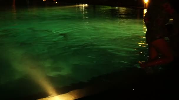 Piernas femeninas en la piscina nocturna . — Vídeo de stock