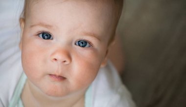 Bebek duygular. Beyaz t shirt mavi gözlü kız bebek bakmak cam içinde. Yeni doğan. Yakın çekim.