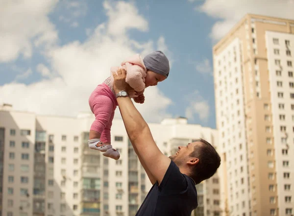 Mutlu bir aile. Baba kızın kollarında tutar. Şehir arka plan.