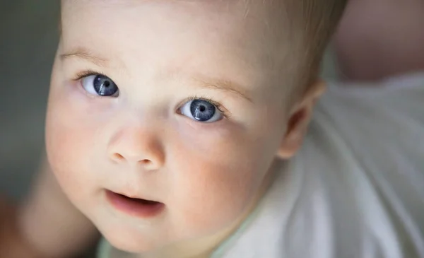 Bebek duygular. Beyaz t shirt mavi gözlü kız bebek bakmak cam içinde. Yeni doğan. Yakın çekim.