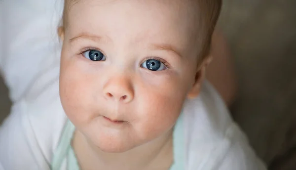 Bebek duygular. Beyaz t shirt mavi gözlü kız bebek cam içinde bakmak ve öpmeye çalışın. Yeni doğan. Yakın çekim.