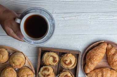 Bir fincan kahve ve tahta tabakta doğranmış domuz çöreği.