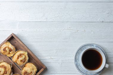 Bir fincan kahve ve tahta tabakta doğranmış domuz çöreği.