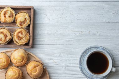 Bir fincan kahve ve tahta tabakta doğranmış domuz çöreği.