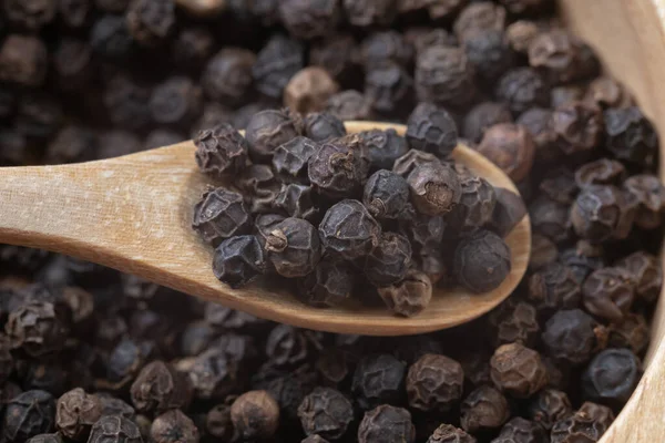 Close up of pile black pepper and wooden spoon Royalty Free Stock Photos