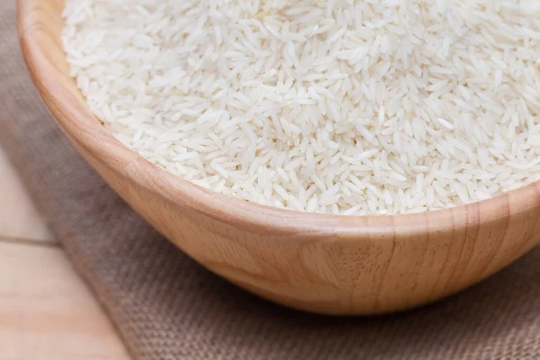 Close up de arroz branco cru em tigela de madeira — Fotografia de Stock