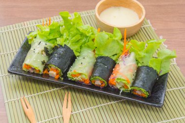 close up of vegetable salad roll and sauce