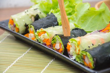 close up of vegetable salad roll and sauce