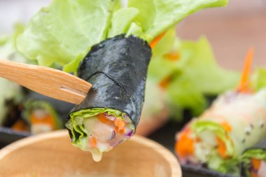 close up of vegetable salad roll and sauce