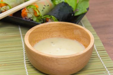 close up of vegetable salad roll and sauce