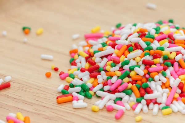 Fermer les arrosages colorés de l'arc-en-ciel sur une assiette en bois — Photo