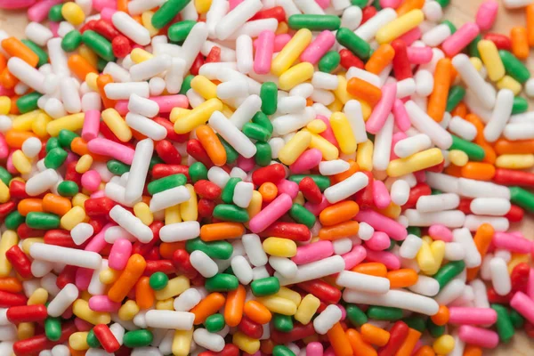 Close up colorful rainbow sprinkles on wooden plate — Stock Photo, Image