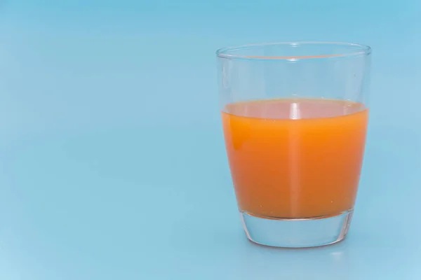 Uma xícara de suco de laranja no fundo azul claro — Fotografia de Stock