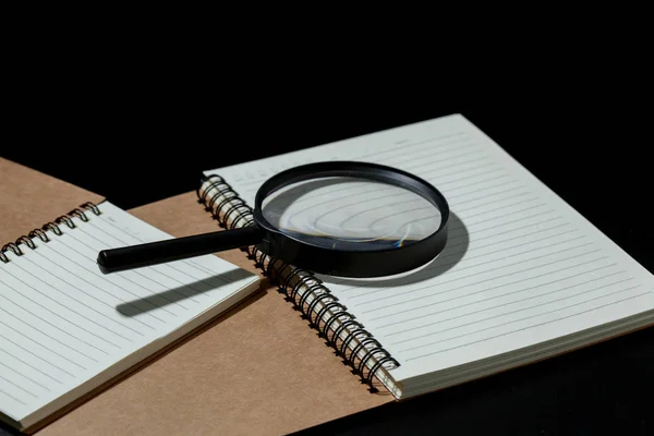 Lupa a notebook na černém pozadí, prozkoumat c — Stock fotografie