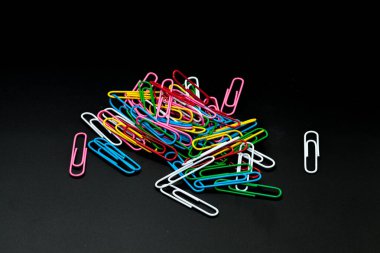 Siyah arkaplanda farklı renkte ataç yığını