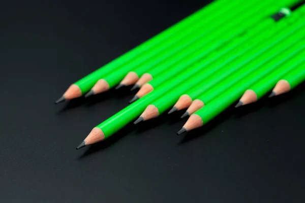 Green pencil on black background, leadership concept — Stock Photo, Image