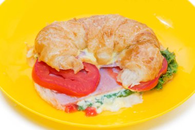 Sarı tabakta kruvasan jambon ve peynir.