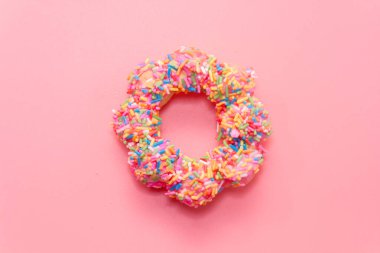 close up of colorful doughnut on pink background