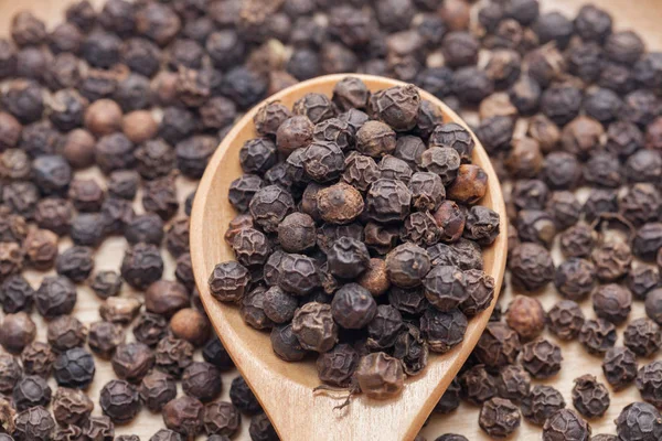 Close up of Whole Black Pepper On Wooden Spoon — стоковое фото