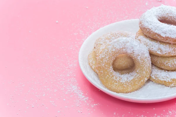 Smażone pączki na różowym tle z polewą cukrową w proszku — Zdjęcie stockowe