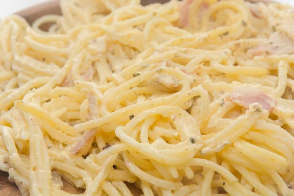 Spaghetti carbonara z kremem na drewnianym talerzu na białym tle — Zdjęcie stockowe